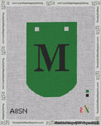 A taped needlepoint canvas with the design: Banner 18 mesh count Curved M Black on Green.