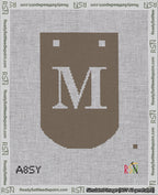 A taped needlepoint canvas with the design: Banner 18 mesh count Curved M White on Brown.