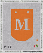 A taped needlepoint canvas with the design: Banner 18 mesh count Curved M White on Orange.