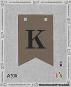 A taped needlepoint canvas with the design: Banner 18 mesh count Forked K Black on Brown.