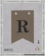 A taped needlepoint canvas with the design: Banner 18 mesh count Forked R Black on Brown.