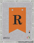A taped needlepoint canvas with the design: Banner 18 mesh count Forked R Black on Orange.