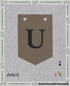 A taped needlepoint canvas with the design: Banner 18 mesh count Pointed U Black on Brown.