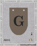 A taped needlepoint canvas with the design: Banner 18 mesh count Rounded G Black on Brown.