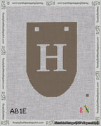 A taped needlepoint canvas with the design: Banner 18 mesh count Rounded H White on Brown.