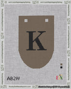 A taped needlepoint canvas with the design: Banner 18 mesh count Rounded K Black on Brown.