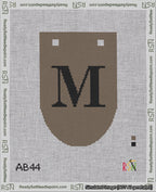A taped needlepoint canvas with the design: Banner 18 mesh count Rounded M Black on Brown.