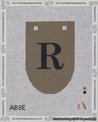 A taped needlepoint canvas with the design: Banner 18 mesh count Rounded R Black on Brown.