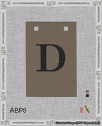 A taped needlepoint canvas with the design: Banner 18 mesh count Squared D Black on Brown.