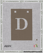 A taped needlepoint canvas with the design: Banner 18 mesh count Squared D White on Brown.