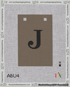 A taped needlepoint canvas with the design: Banner 18 mesh count Squared J Black on Brown.
