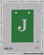 A taped needlepoint canvas with the design: Banner 18 mesh count Squared J White on Green.