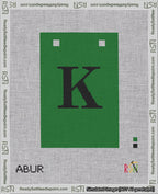 A taped needlepoint canvas with the design: Banner 18 mesh count Squared K Black on Green.