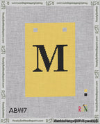 A taped needlepoint canvas with the design: Banner 18 mesh count Squared M Black on Yellow.