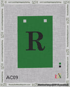 A taped needlepoint canvas with the design: Banner 18 mesh count Squared R Black on Green.