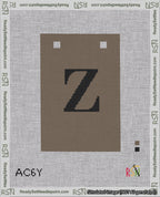 A taped needlepoint canvas with the design: Banner 18 mesh count Squared Z Black on Brown.