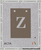 A taped needlepoint canvas with the design: Banner 18 mesh count Squared Z White on Brown.