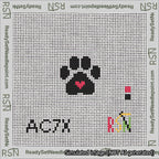 A taped needlepoint canvas with the design: Square Cat Paw Print Black On White with Red Heart.