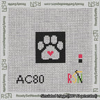 A taped needlepoint canvas with the design: Square Cat Paw Print White On Black with Red Heart.